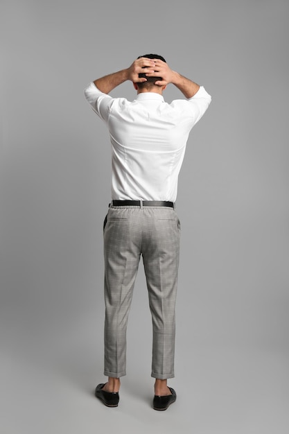 Businessman in formal clothes on grey background back view