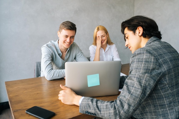 Businessman in formal wear giving presentation to colleagues at meeting in boardroom Business people at conference room looking at laptop screen