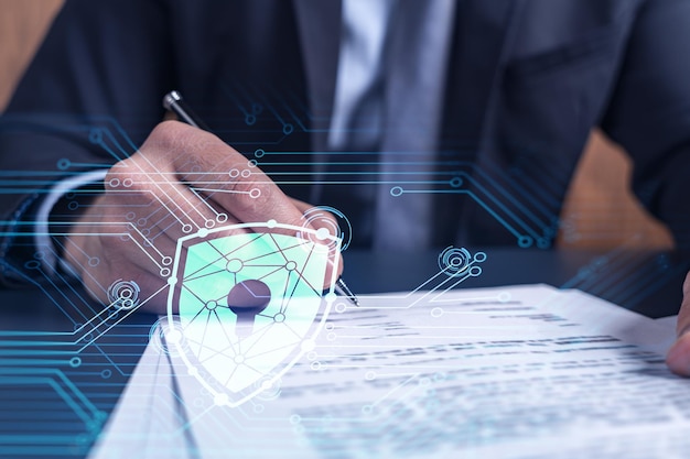 A businessman in formal wear signing the contract to prevent\
probability of risks in cyber security padlock hologram icons over\
the working desk