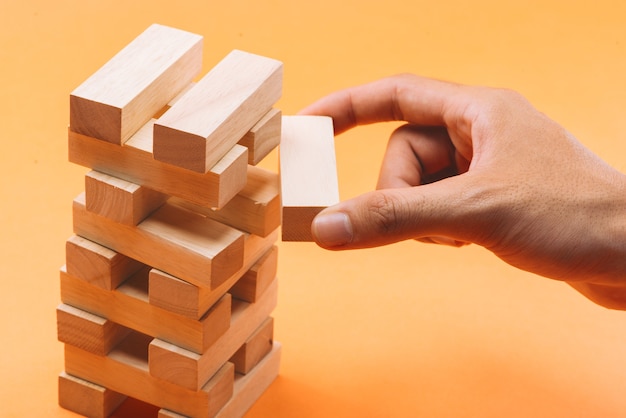 Businessman gambling placing wooden block on a tower