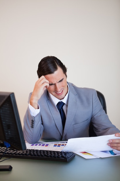 Businessman getting a headache from looking at paperwork