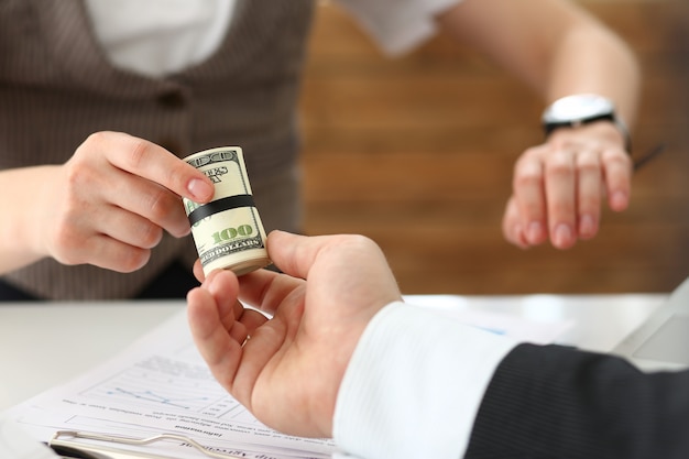 Businessman gives a cutlet from money to a woman in the form of a salary bribe in an envelope dollar equivalent