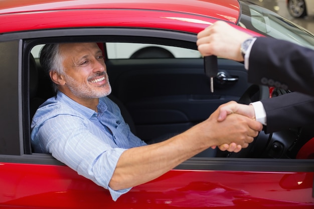 Photo businessman giving car key while shaking a customer hand