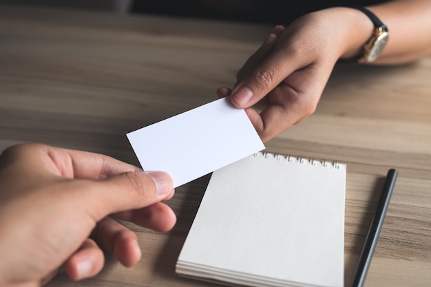 Businessman giving an empty business card to businesswoman with a notebook 