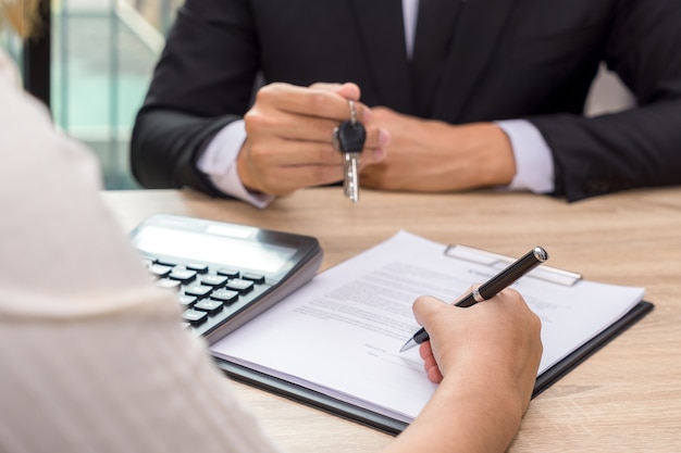 Businessman giving house keys and customer signing loan agreement