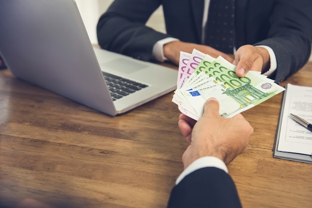 Businessman giving money, Euro banknotes, to his partner while making contract