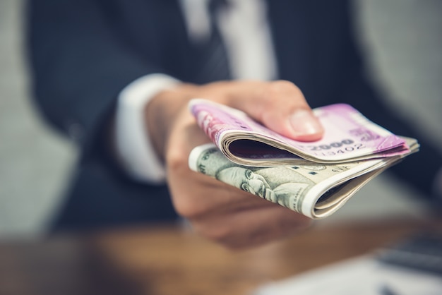 Businessman giving money in the form of Indian Rupees currency