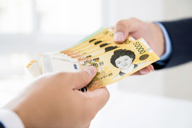 Businessman giving money to his partner in form of South Korean Won