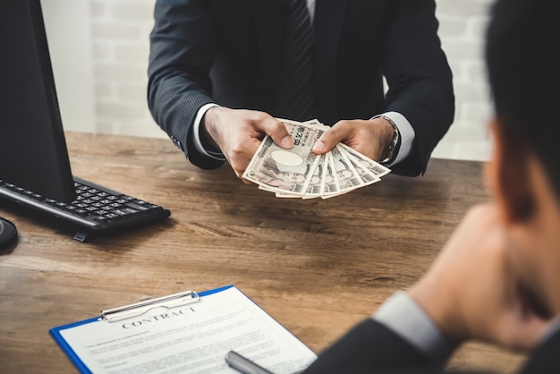 Businessman giving money, Japanese yen banknote, to his partner while making contract