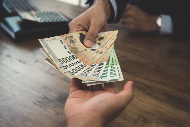 Photo businessman giving money, korean won banknotes, to his partner