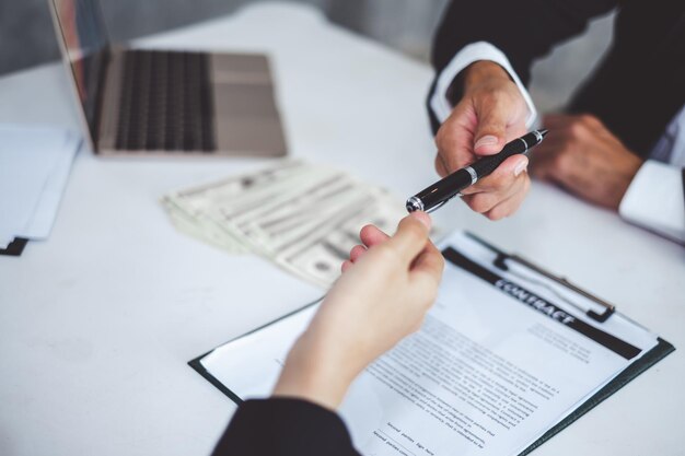 Businessman giving pen to businesswoman for signing contract banking money loaning