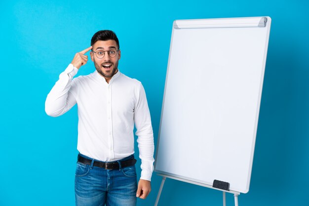 Uomo d'affari che dà una presentazione sul bordo bianco che dà una presentazione sul bordo bianco e che intende realizzare la soluzione