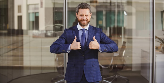 Businessman giving thumbs up business man going thumb up near the office