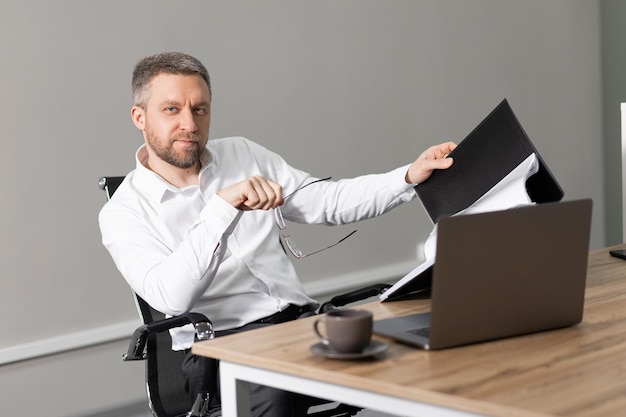 Бизнесмен серый человек в современном офисе В руках он держит папку для бумаг