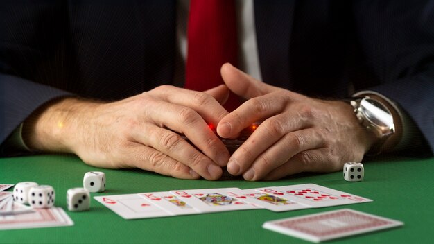 Businessman at green gaming table with game chips, cards and dice playing poker and blackjack in casino