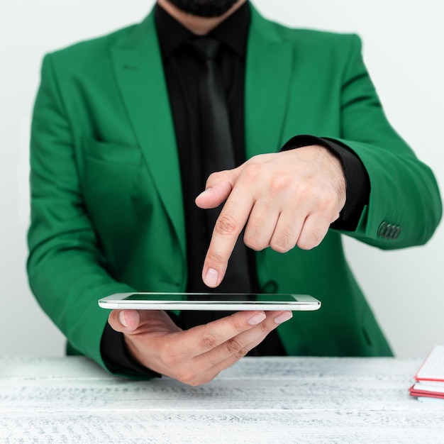 Businessman in Green jacket sitting at table holding mobile phone And Pointing With One Finger On Important Message Gentleman Showing Critical Announcement