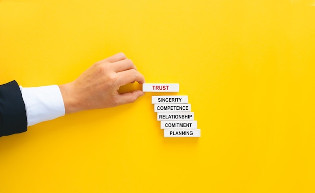 Businessman hand building wooden blocks with Trust concept.