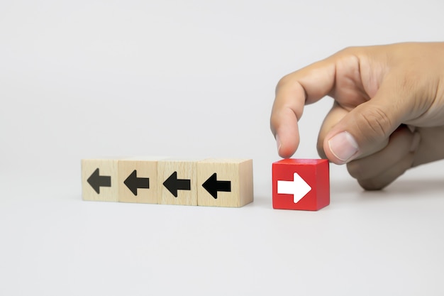 Businessman hand chooses cube wooden toy blog with arrow head icons pointing to opposite directions