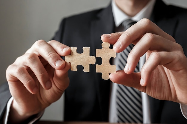 Businessman hand connecting jigsaw puzzle.Business solutions, success and strategy concept.