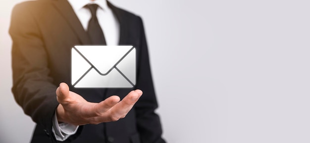 Businessman hand holding e-mail icon, Contact us by newsletter email and protect your personal information from spam mail. Customer service call center contact us concept