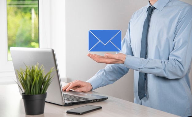 Photo businessman hand holding e-mail icon, contact us by newsletter email and protect your personal information from spam mail. customer service call center contact us concept.