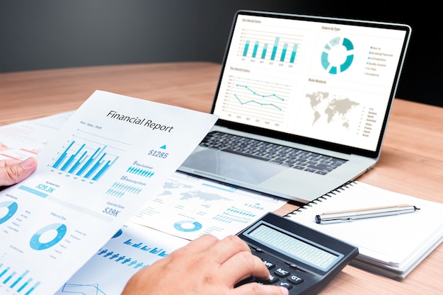 Businessman hand holding financial report document with mock up\
chart presentation on display laptop