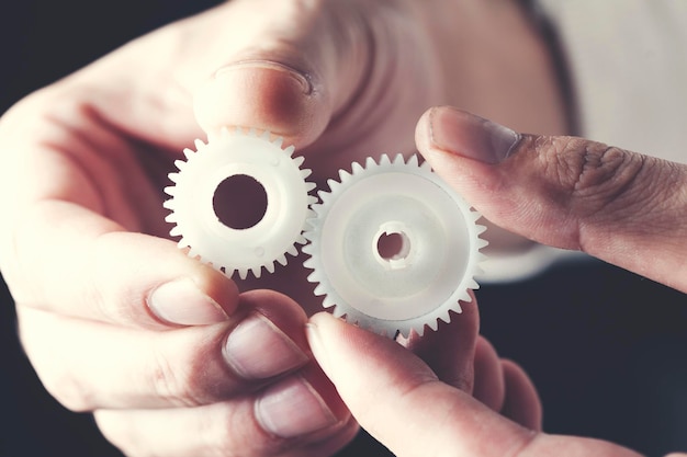 Businessman hand holding gear elements on dark background