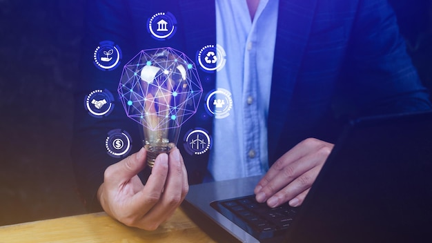 Businessman hand holding light bulb with ESG icon concept for environmental social and governance in sustainable and ethical business on the Network connection