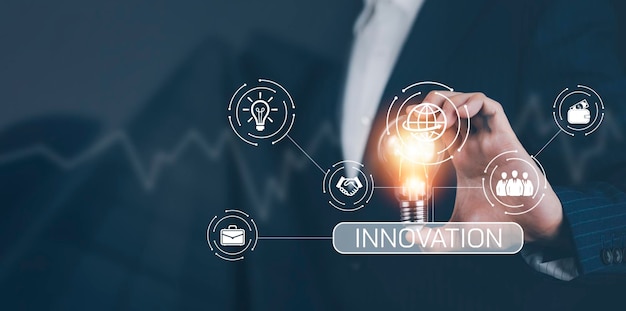 Businessman hand holding light bulb with icons and working on the desk Creativity and innovation are keys to successConcept of new idea and innovation with energy and power working at home