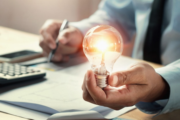 Businessman hand holding lightbulb in office. 