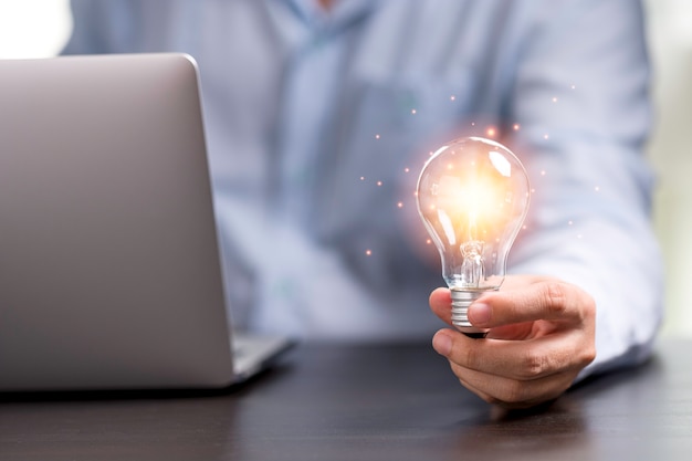 Photo businessman hand holding lightbulb with orange glowing for creative thinking idea concept.