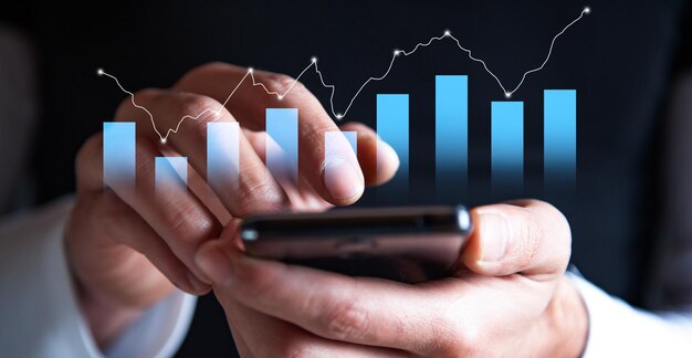 Mano dell'uomo d'affari che tiene il telefono cellulare e mostra un grafico del diagramma delle statistiche