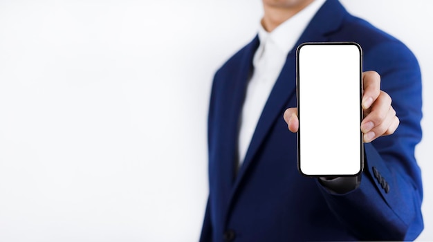 Businessman hand holding mobile white blank screen Mock up cell mobile smart phone  in suit holds mobile phone with blank white screen on dark blue backgroundonline business concept