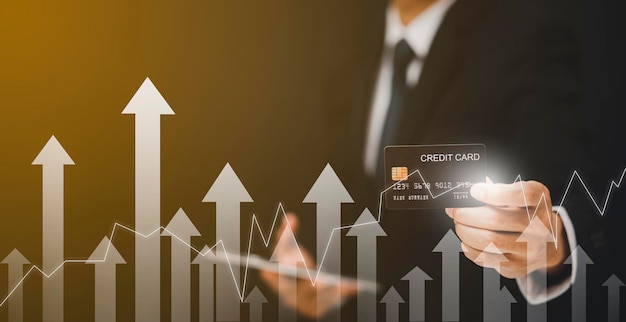 Businessman hand holding Model credit card with arrow graph of market stock and using mobile phone. Online shopping concept, banking and online shopping at the home.Close up. copy space,