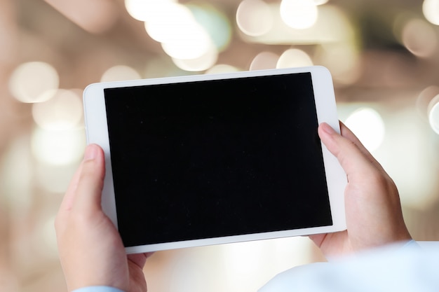 Businessman hand holding tablet with blank on screen display over blur background