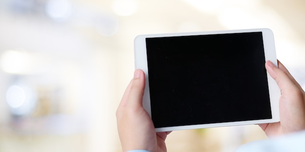 Businessman hand holding tablet with blank on screen display over blur background