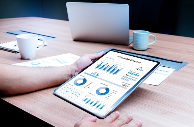 Businessman hand holding tablet with financial report slide show presentation on display