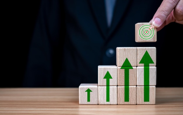 Photo businessman hand holding a wooden block which prints a target icon business goals and objectives concept business competition