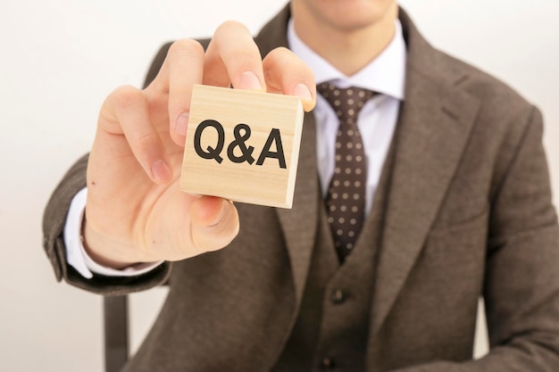 Businessman hand holding wooden block with the text q and a