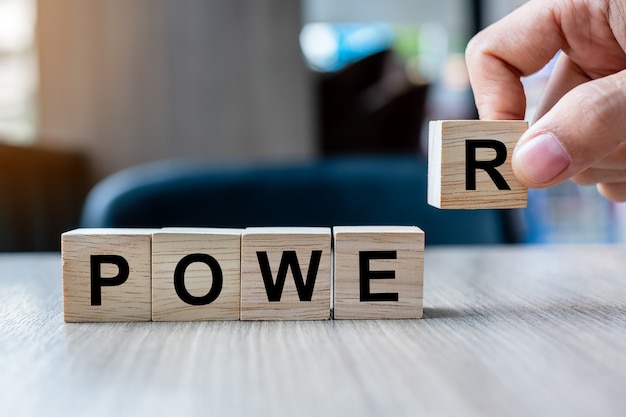 Businessman hand holding wooden cube block with POWER business word. Words Have Power concept