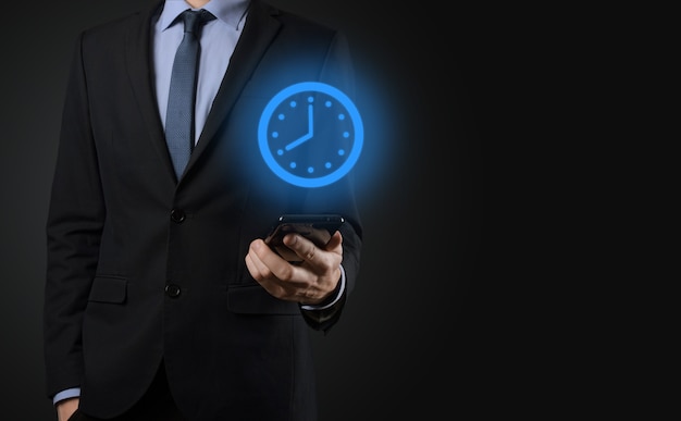 Businessman hand holds the icon of hours clock with arrow. Rapid execution of the work