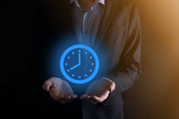 Businessman hand holds the icon of hours clock with arrow