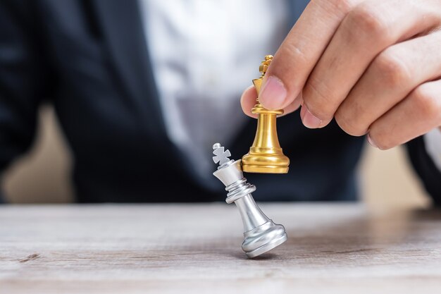Mano di uomo d'affari in movimento figura di re degli scacchi d'oro durante la competizione di scacchiera.