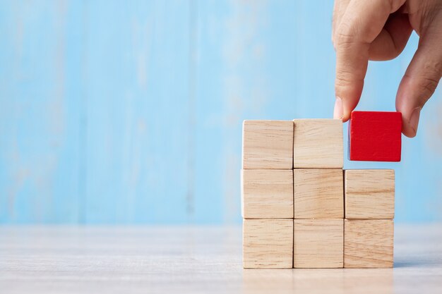 Businessman hand placing or pulling Red wooden block on the building