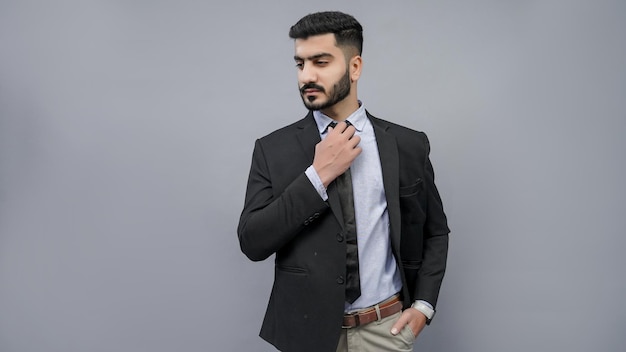 businessman hand in pocket holding tie looking left in black suit indian pakistani model