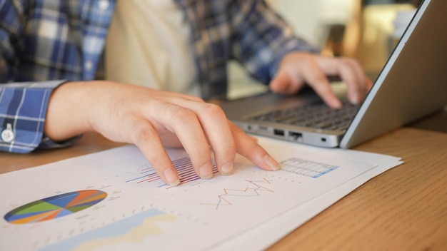 businessman hand pointing in dashboard statistic chart report on in office room