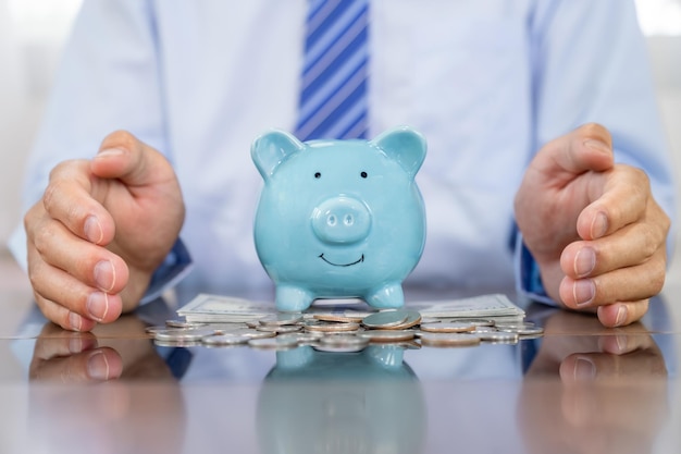 Photo businessman hand prevent blue piggy bank saving money for future plan and retirement fund concept