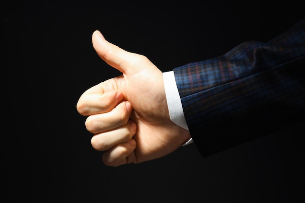 Businessman hand show thumb up on dark background