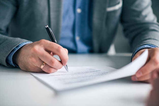 Businessman hand signing contract, close-up.