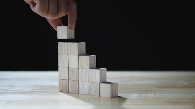 Businessman hand stacking wood block as step stair business development business growth success
